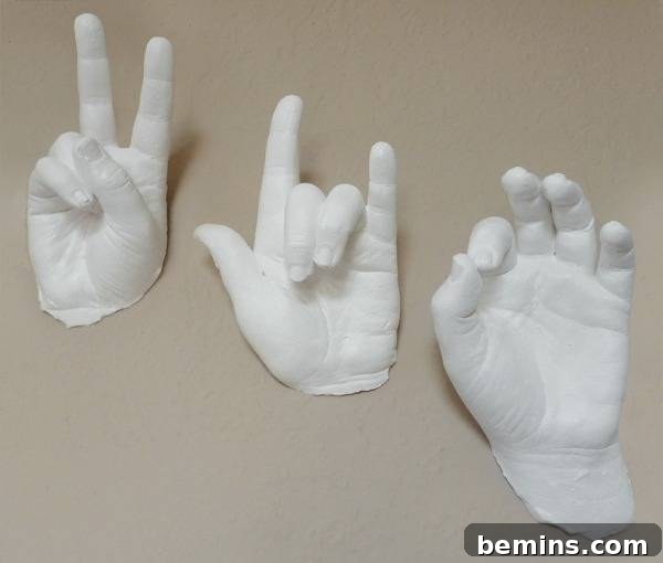 A white hand statue making a piece sign next to a white hand statue making a hang loose sign next to a white hand statue making the okay sign.