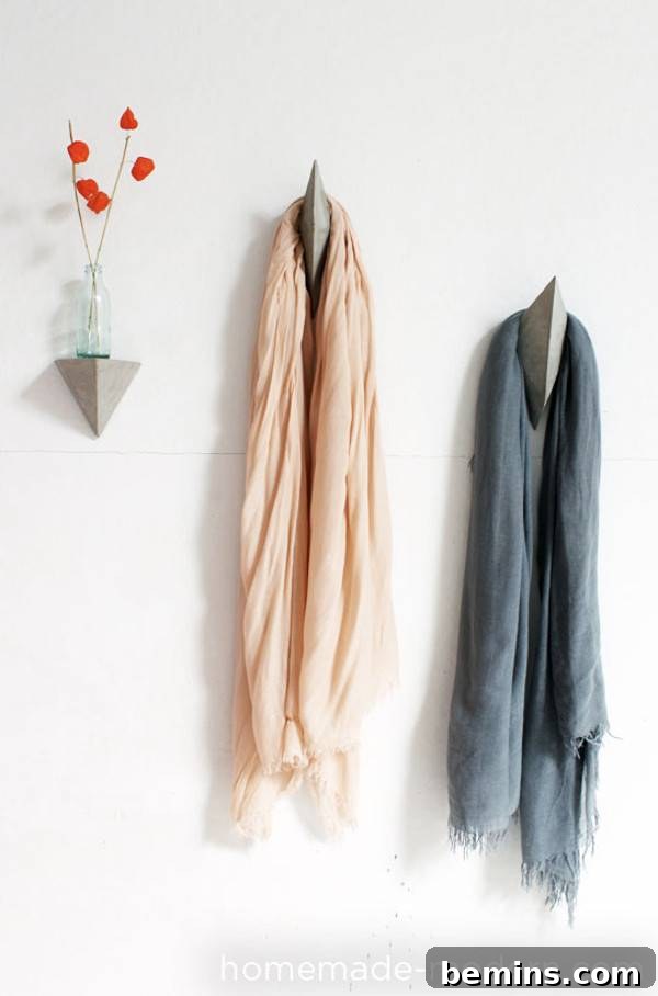 Cloths are hanged to the wall hooks and a flower vase is on the wall.