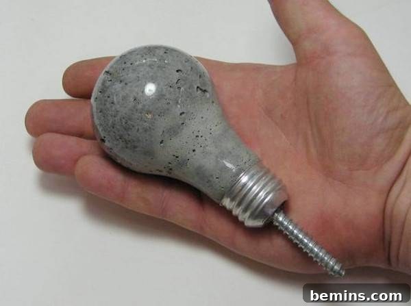 Man holding a grey light bulb in his hand that has a screw coming out of the bottom of it.