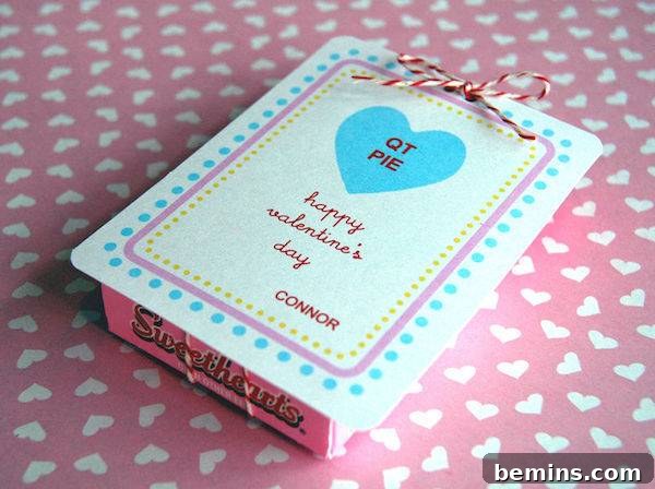 A box with blue dots and a blue hear with the words QT PIE in it laying on a pink table cloth with white hearts.