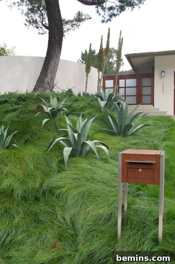 Modern stainless steel mailbox with a four-legged design sitting on a lawn.