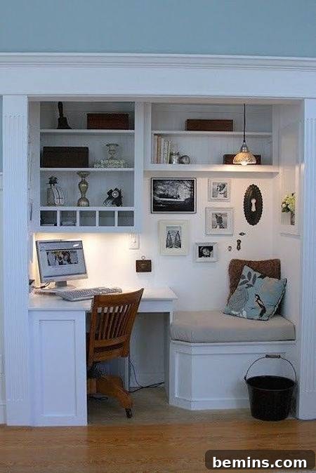 A white working office desk with a side couch and a brown chair, showcasing smart built-in design within an alcove or closet space.