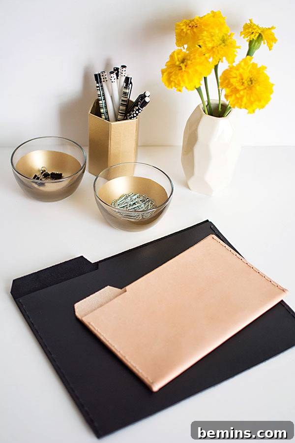 Manila file folders sit on top of black file folders on a white desk with pretty yellow flowers on it.