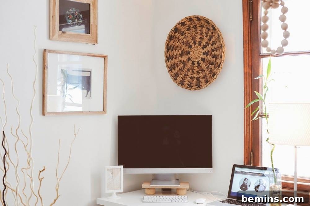 Paintings and artwork are hanging on the wall near a workspace near a window.