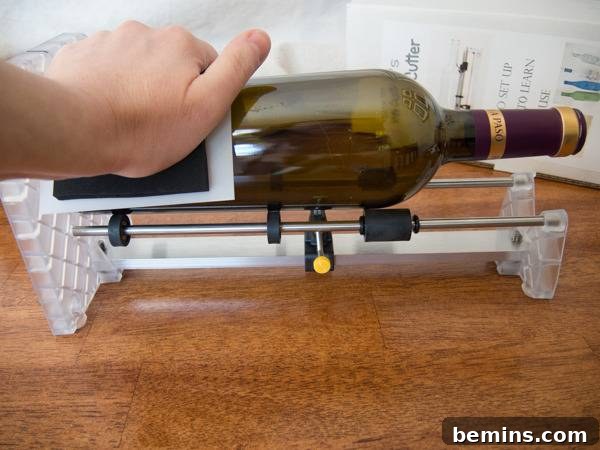 Which Bottle Cutter Reigns Supreme? A Definitive Review 39 Hand holding a horizontal empty glass wine bottle on a bottle cutter, on a wood surface.