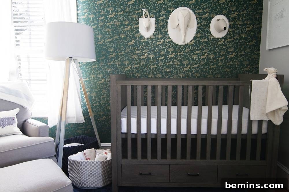 A beautifully decorated baby boy's nursery with a modern crib, a plush glider, and a statement hunter green safari wallpaper. The room features a balance of bold colors and soft textures.