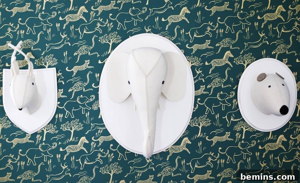 Close-up of a safari-themed wall in a baby's nursery, showcasing charming wall sculptures of a deer, elephant, and panda against a backdrop of hunter green wallpaper, subtly bringing the outdoors in.