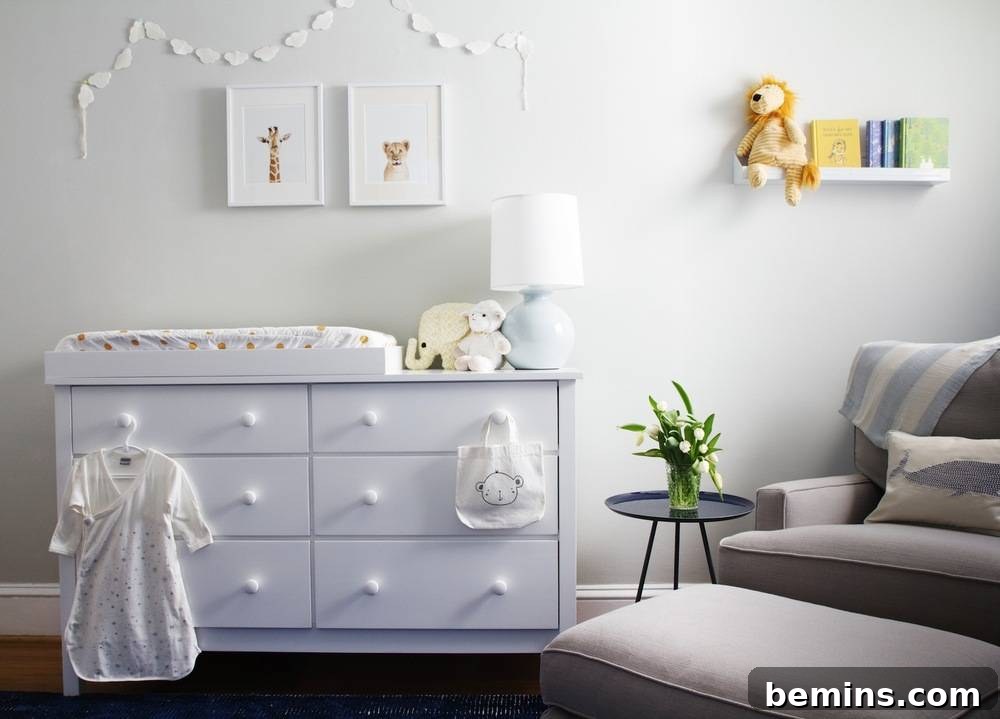 A serene corner of the nursery featuring white and gray elements, including a dresser, a hanging dress, and a picture lamp, creating a clean and bright aesthetic against the themed wall.