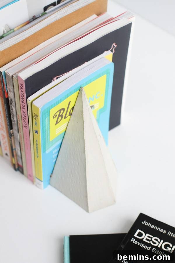 DIY Geometric Concrete Bookends from Recycled Cardboard 15 A white pyramid shaped cone holds up some books.