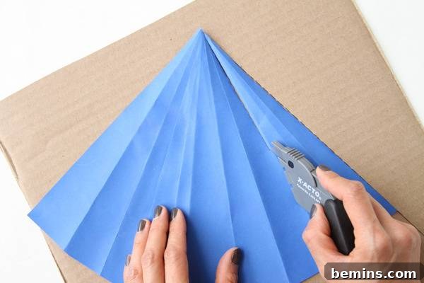 DIY Geometric Concrete Bookends from Recycled Cardboard 5 Cutting blue paper on a cardboard surface.