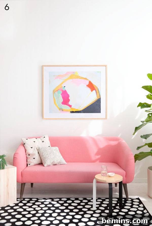 Pink couch on a black and white carpet with colorful artwork.