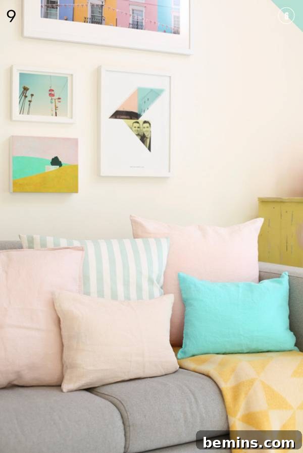 Pastel pillows on a gray couch with framed artwork.