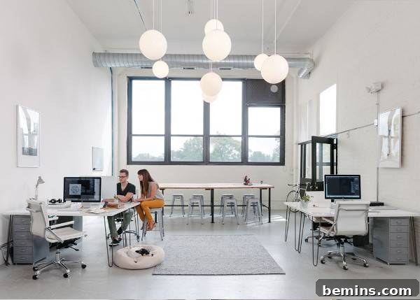 Open design studio with high ceilings and wooden floor filled with work stations. The KNOED studio promotes collaboration and teamwork.