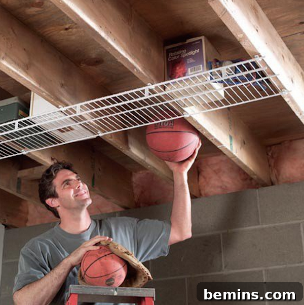 A man storing basketballs in an overhead attic shelf, showcasing how to utilize overhead space for storage.