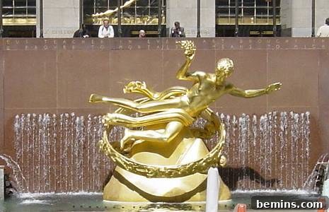 A golden statue of an Athenian man next to a waterfall.