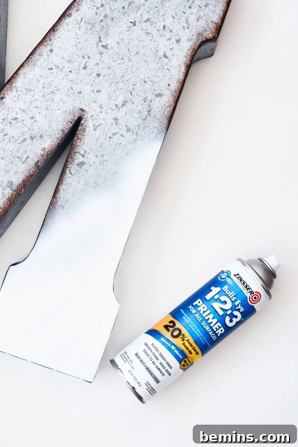 A pristine white capital letter M, spray-painted and ready, lies next to its spray paint can, signifying the completion of the base coat.