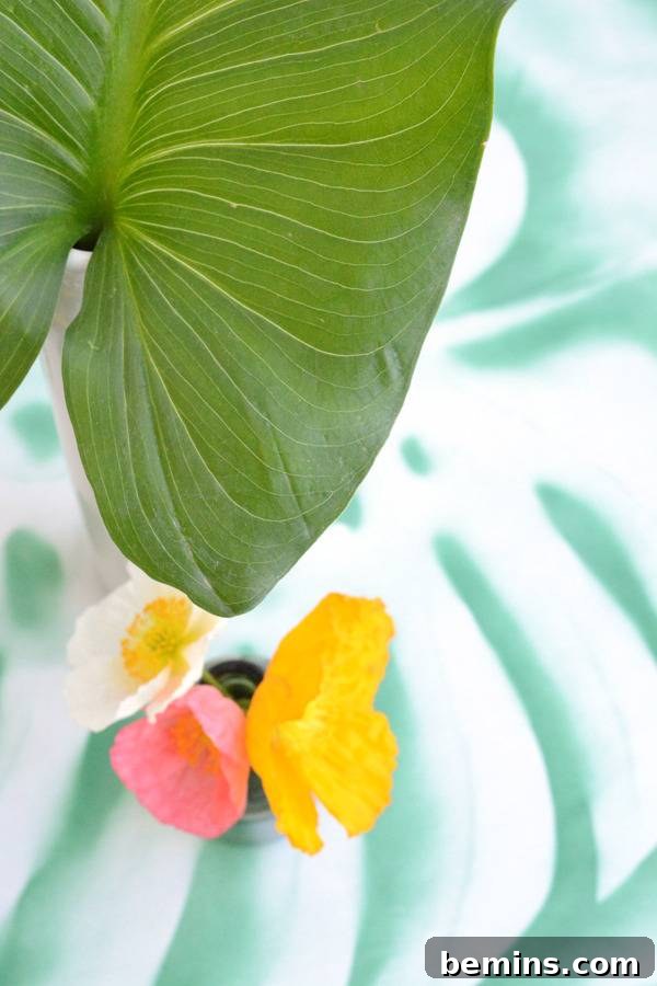 DIY Tropical Leaf Tablecloth Project 12 A large green tropical leaf displayed alongside a smaller yellow leaf and a pink bloom.