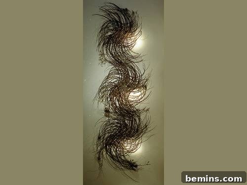A mesmerizing twig sculpture with threads weaving around in a vertical arrangement, beautifully illuminated by strategically placed lights that create a dramatic visual effect.