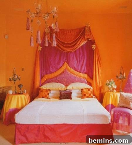 A middle eastern style bedroom has orange walls, and hot pink trim on the bed with the hot pink and orange tassel headboard of fabric.