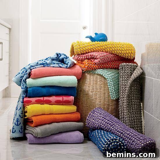 Stack of colorful towels and rolled towels on top of a hamper, showcasing Fresh Start Bath Mats