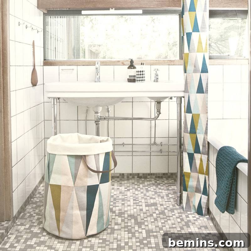 Bathroom with a white sink, tub, shower curtain, and Spear Laundry Basket