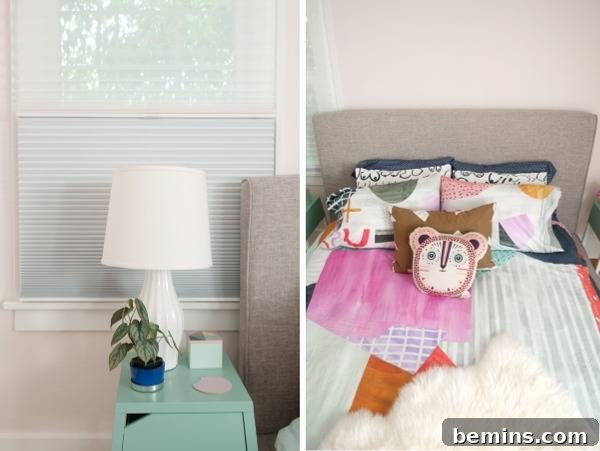 A bedside table with a lamp and decorative items, with window shades in the background.