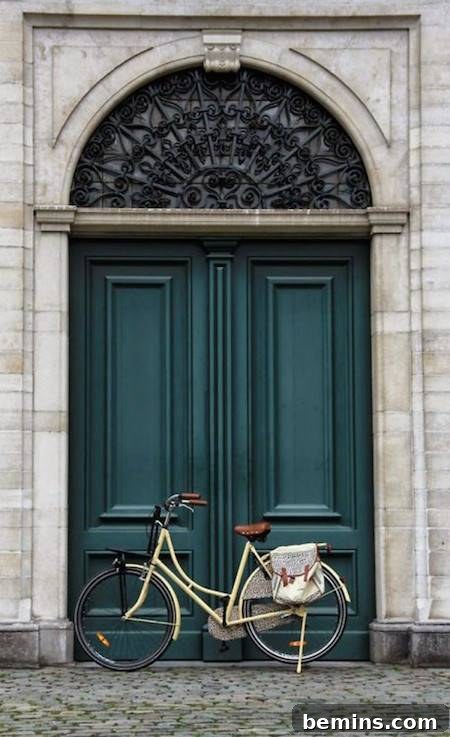 A bike parked in the door frame of a large double blue-green door, creating a stylish and inviting entrance.