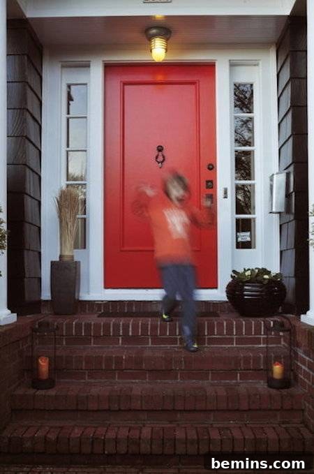A boy in an orange shirt coming down the stairs from a house with a red-orange door, creating a warm and inviting scene.