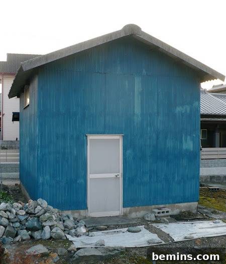A white door providing entrance into a blue building, creating a clean and minimalist contrast.