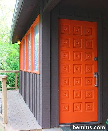 A modern dark grey building with a striking orange door and orange accents around the windows, creating a bold and contemporary look.