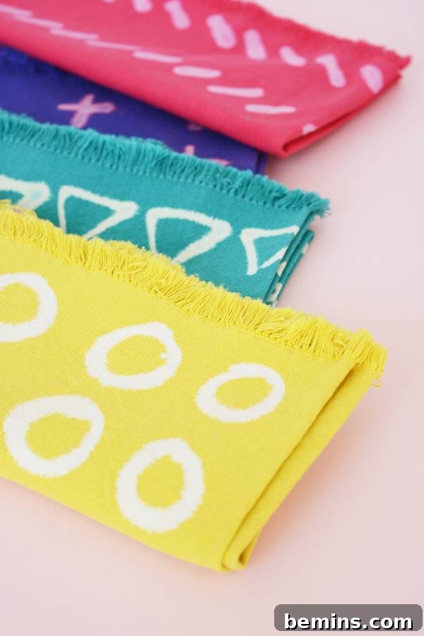 DIY Bleach Stenciled Geometric Napkins 3 Geometric shapes are painted on pink, blue, teal, and yellow napkins.