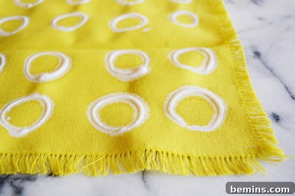 DIY Bleach Stenciled Geometric Napkins 6 A yellow frilly piece of cloth with rows of white rings on it.
