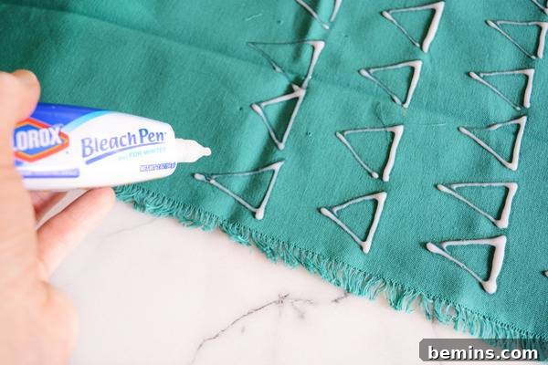 DIY Bleach Stenciled Geometric Napkins 7 A piece of blue fabric has bleach liquid from a bleach pen.