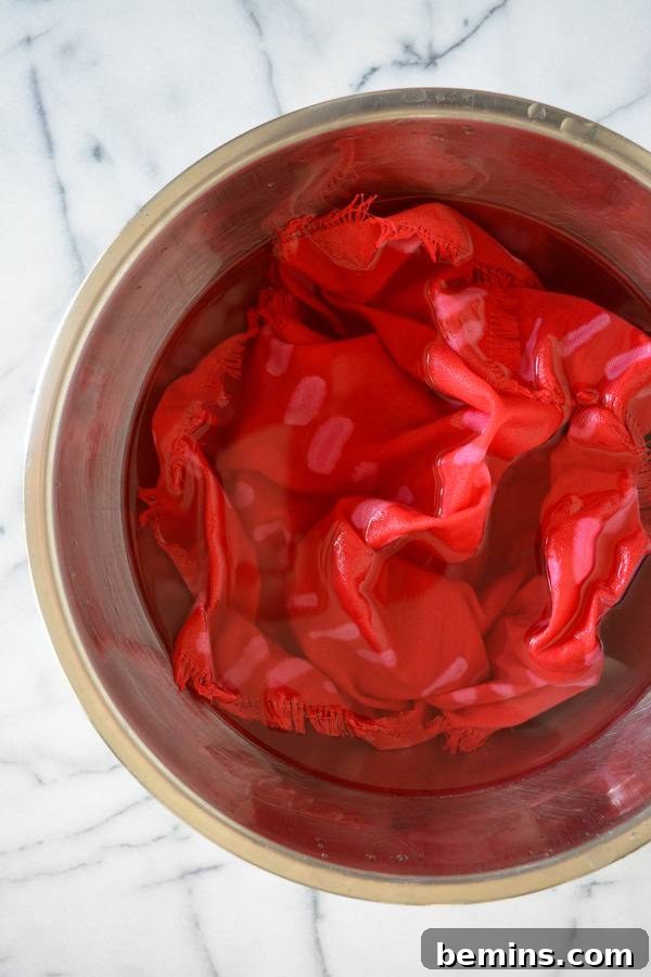 DIY Bleach Stenciled Geometric Napkins 8 A wet piece of red fabric sits in a bowl on a table.