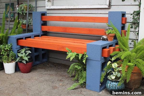 A bench made from blue cinderblocks and red boards surrounded by plants.