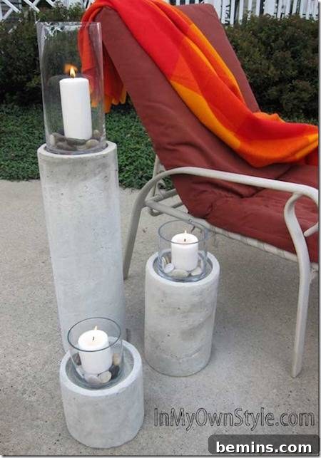 Three ascending hurricane candles outside on pavement next to a lounge chair with a red cushion and orange towel on it.