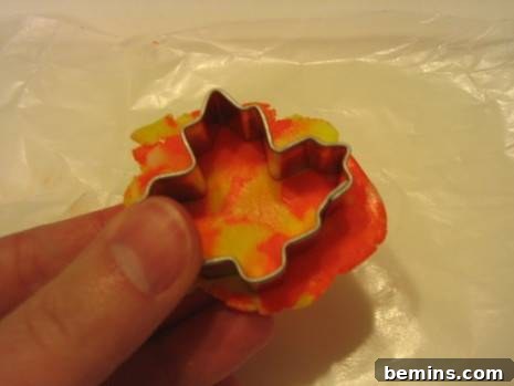 A maple leaf-shaped cookie cutter held by a hand.