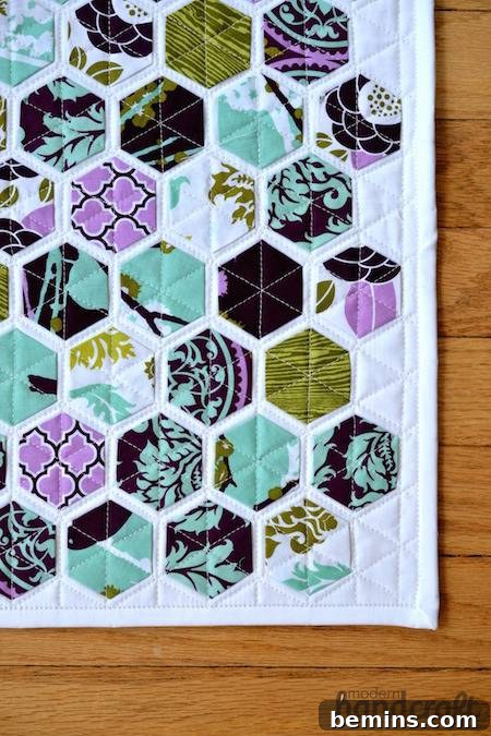 Modern Hexagon Quilt: A Geometric Masterpiece 4 Modern hexagon quilt with purple and light blue colors sitting on top of a wooden floor. A beautifully designed and crafted hexagon quilt.