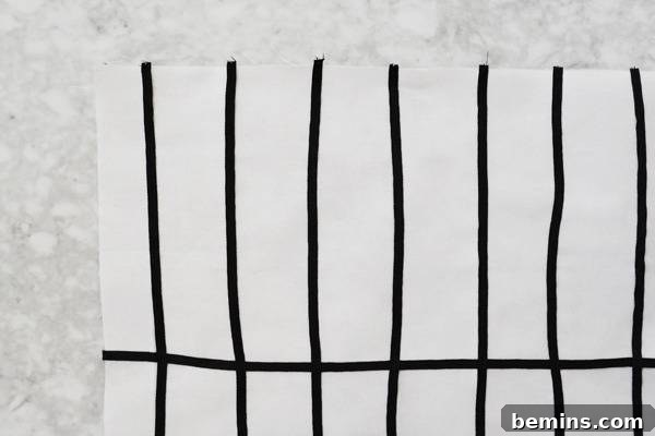 Stylish Geometric Pillows Easy DIY Guide 12 The completed geometric grid pattern on a white fabric square, formed by neatly stitched black grosgrain ribbon lines.
