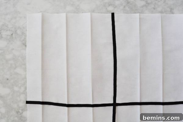 Stylish Geometric Pillows Easy DIY Guide 10 A white fabric square with the initial vertical and horizontal grid lines formed by black grosgrain ribbon, stitched down neatly.
