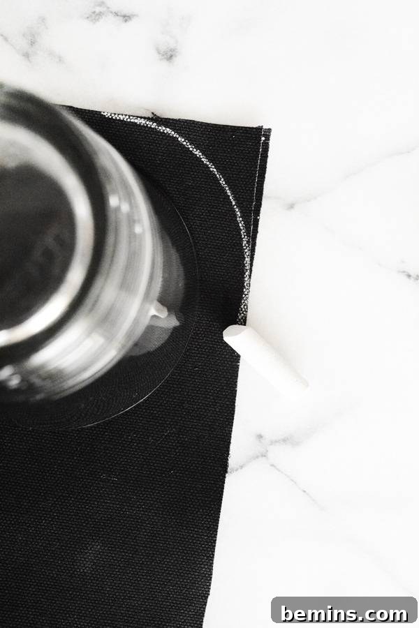 Black paper with white chalk markings and a piece of chalk laying next to it.