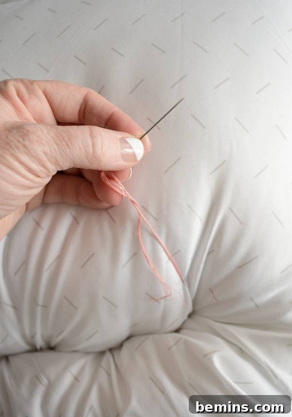 A person is using a needle and thread to sew a pet bed.