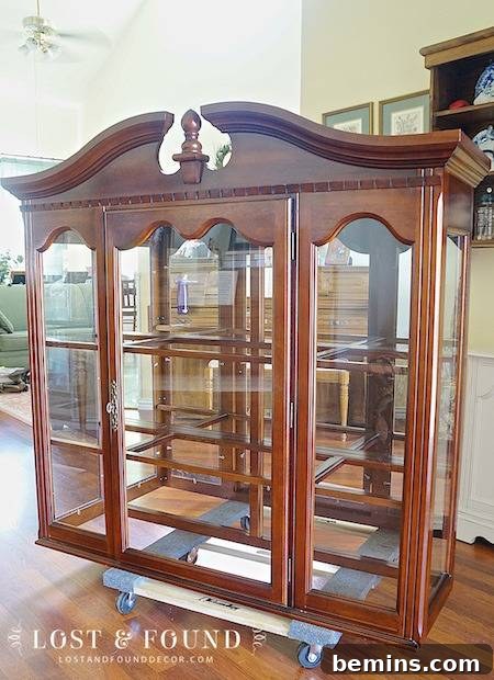 A piece of furniture with wood and glass elements, situated in a room near a wall.