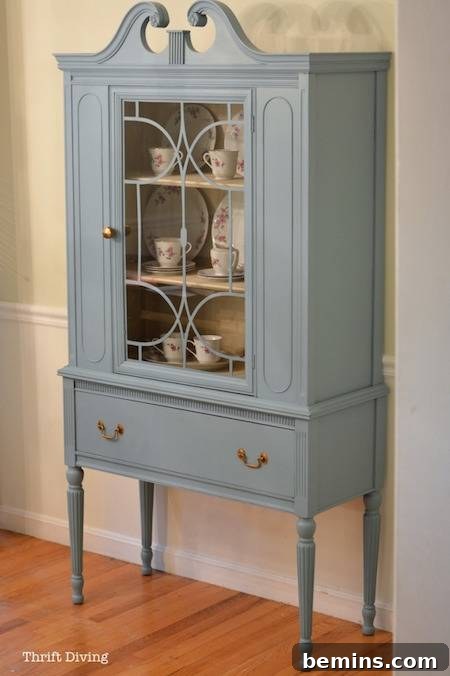 A light blue cabinet with a glass door, adding a touch of elegance to a wooden floor.