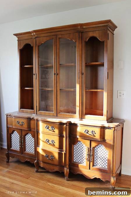 A medium brown wooden hutch with glass doors and four sections, atop a long cabinet with numerous drawers.