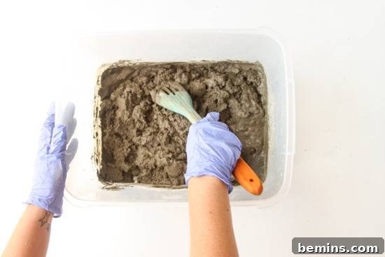 A person is preparing a concrete in a box with big spoon.