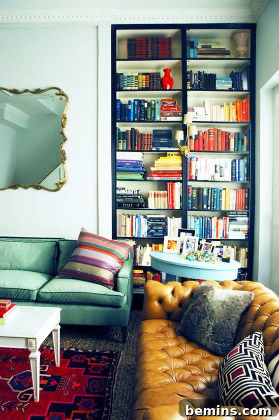 Brown and blue colored couches, bookshelf and mirror in a living room.