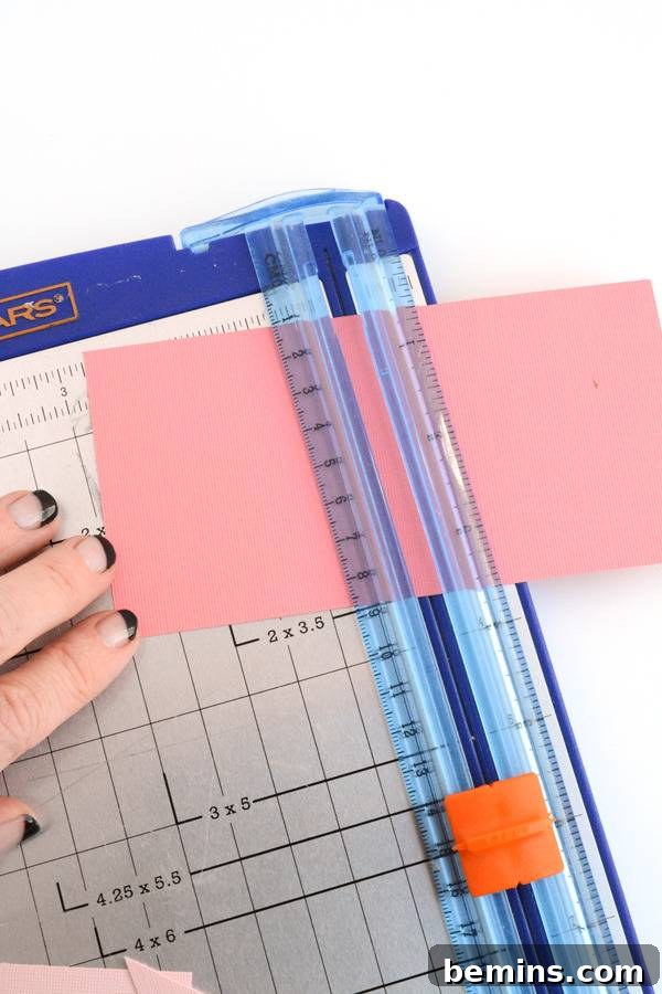 A person puts a pink paper under the ruler in a paper cutter.