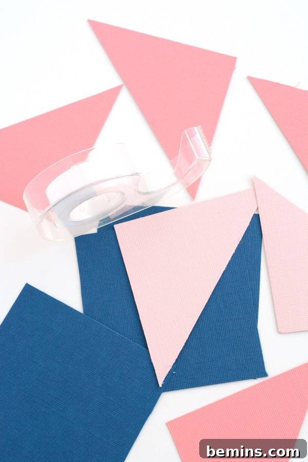 Tape is sitting on pink and blue cut out pieces of paper.