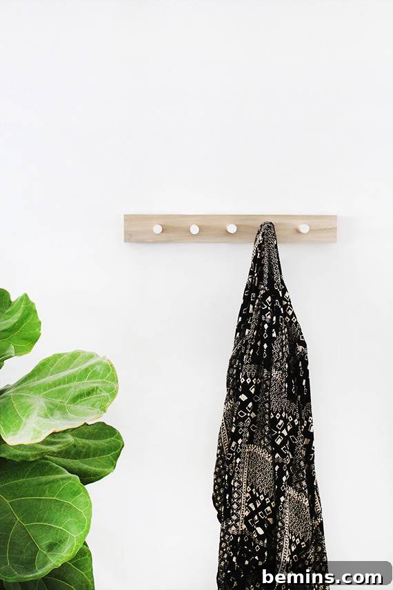 A dark coat is hanging from a wooden coat rack